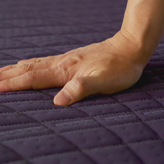 Hand pushing on Purple mattress demonstrating it's medium feel