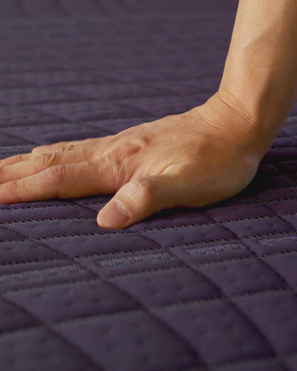 Hand pushing on Purple mattress demonstrating it's medium feel