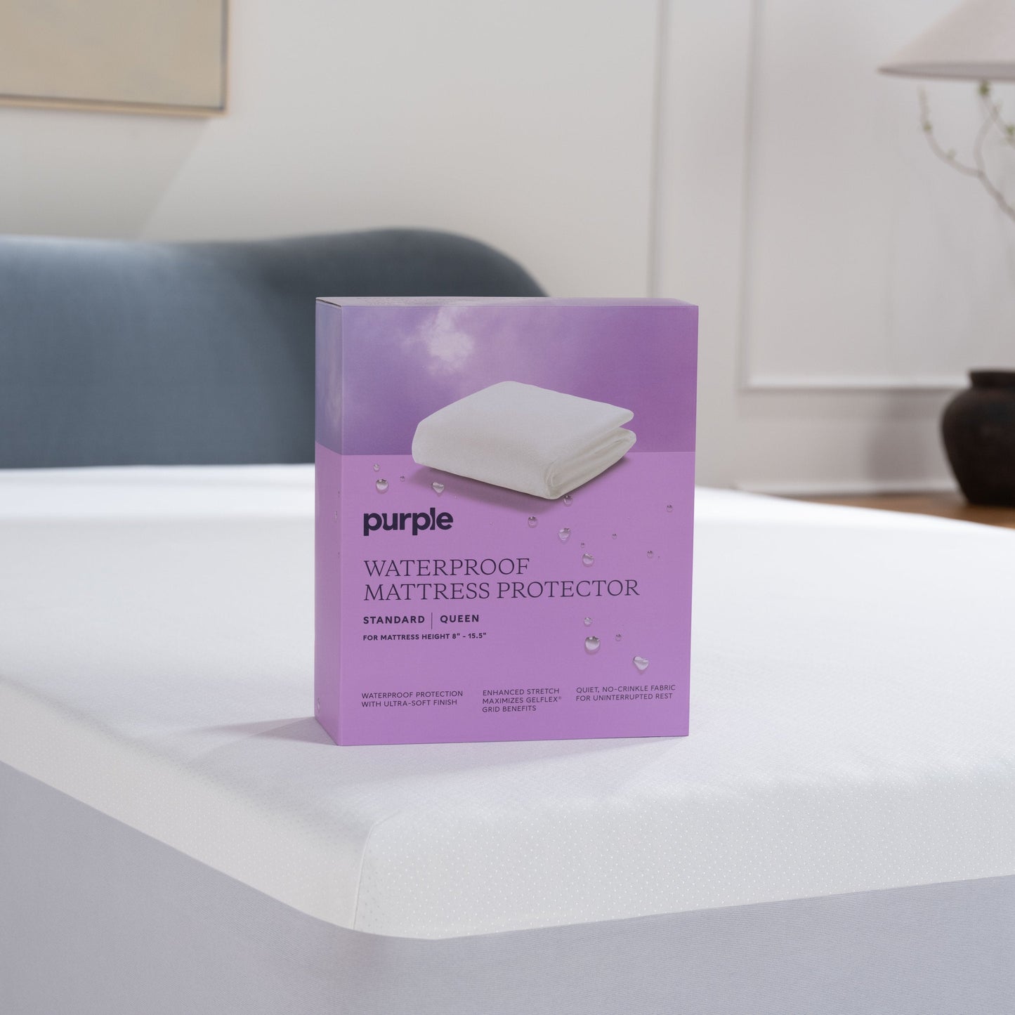 Purple waterproof mattress protector packaging on a bed in a bedroom setting
