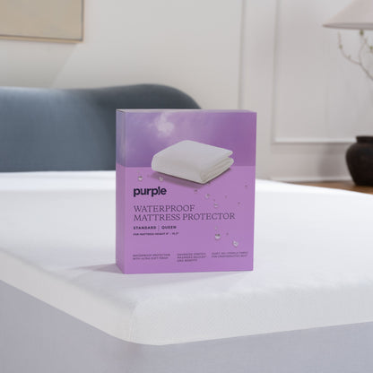 Purple waterproof mattress protector packaging on a bed in a bedroom setting