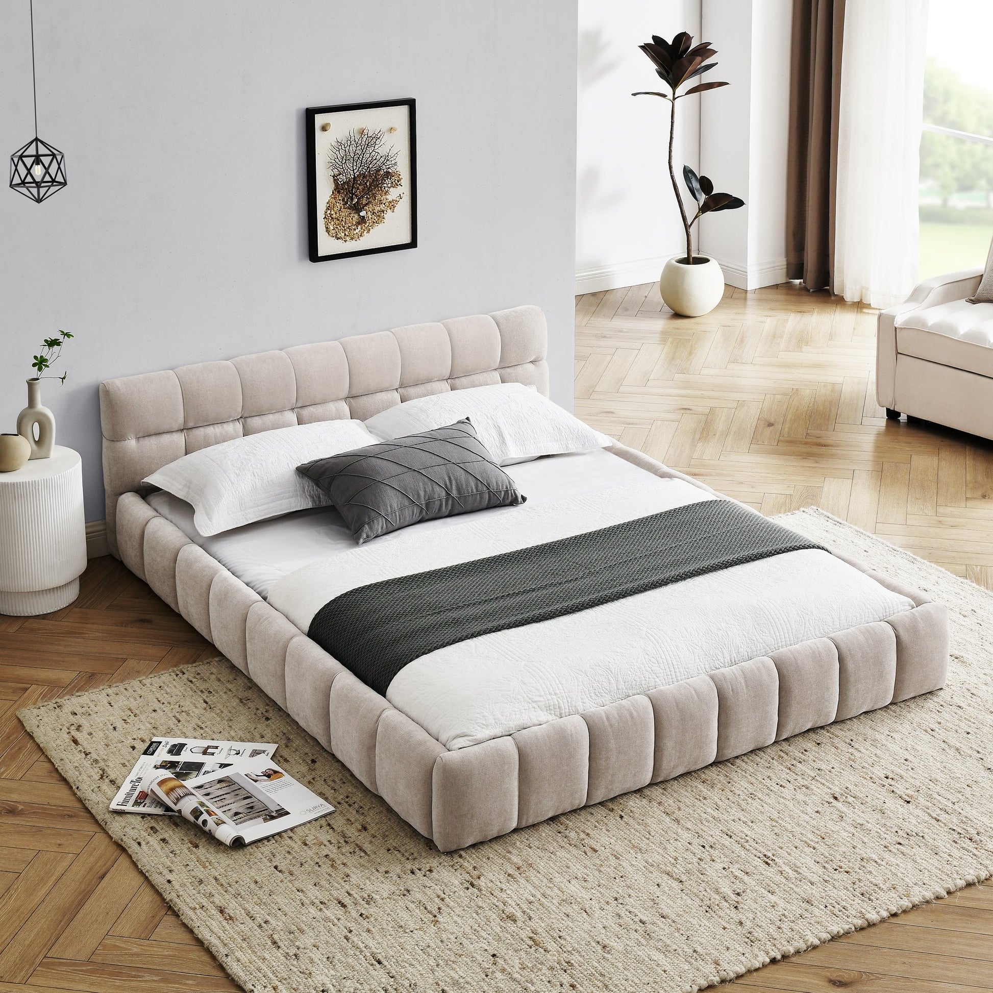 Beige upholstered bed in a modern bedroom with a rug and side table.