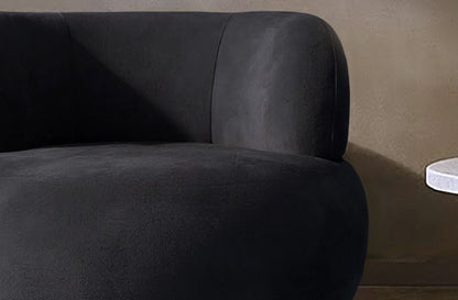 Dark gray luxury accent chair against a brown wall