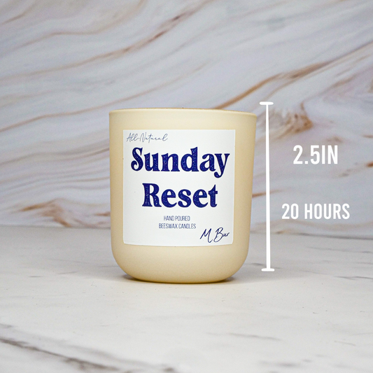candle labeled 'Sunday Reset' with dimensions on a marble background