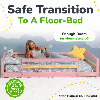 Woman lying on a pink floor-bed with a child, surrounded by stars and clouds, with text about safe transition to a floor-bed.