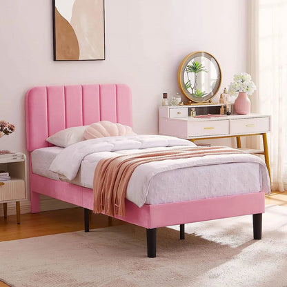 Pink upholstered bed in a bedroom with a vanity table and decor items.
