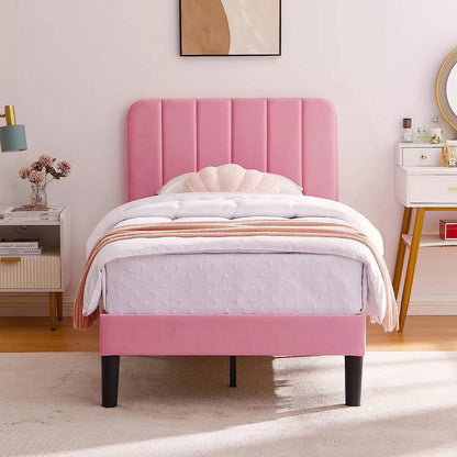 Pink twin upholstered bed in a room with a lamp and decor items.