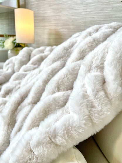 Close-up of a fluffy white blanket on a couch with a blurred background