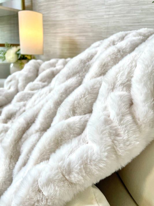 Close-up of a fluffy white blanket on a couch with a blurred background