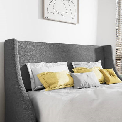 King size gray linen upholstered platform bed with yellow and gray pillows against a white wall.