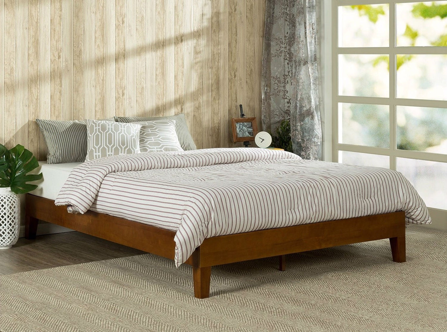 Wooden bed with striped bedding in a room with a window and plant